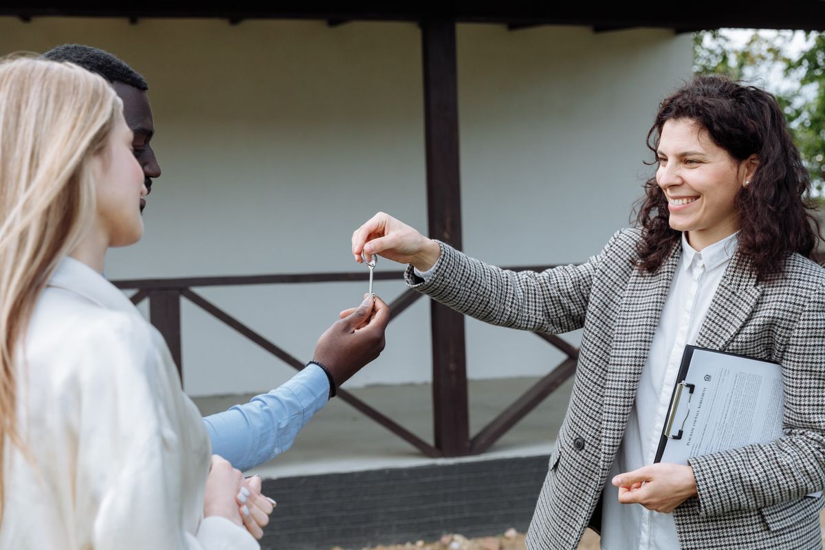Property manager handing house keys to new tenants outside a rental home